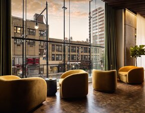 Window-side lounge seating featuring city views, comfortable furnishings, and a relaxing atmosphere in the heart of Row NYC.