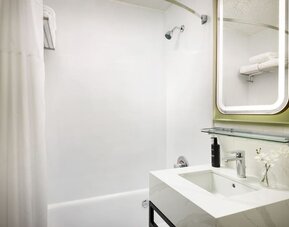 Bright and functional bathroom featuring a full-size bathtub, modern fixtures, and fresh amenities for a comfortable stay at Row NYC.
