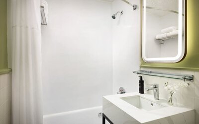 Bright and functional bathroom featuring a full-size bathtub, modern fixtures, and fresh amenities for a comfortable stay at Row NYC.