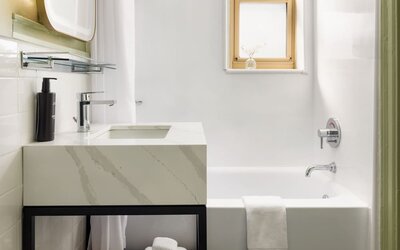 Guest bathroom featuring a spacious bathtub, modern vanity, and clean contemporary décor designed for comfort at Row NYC.