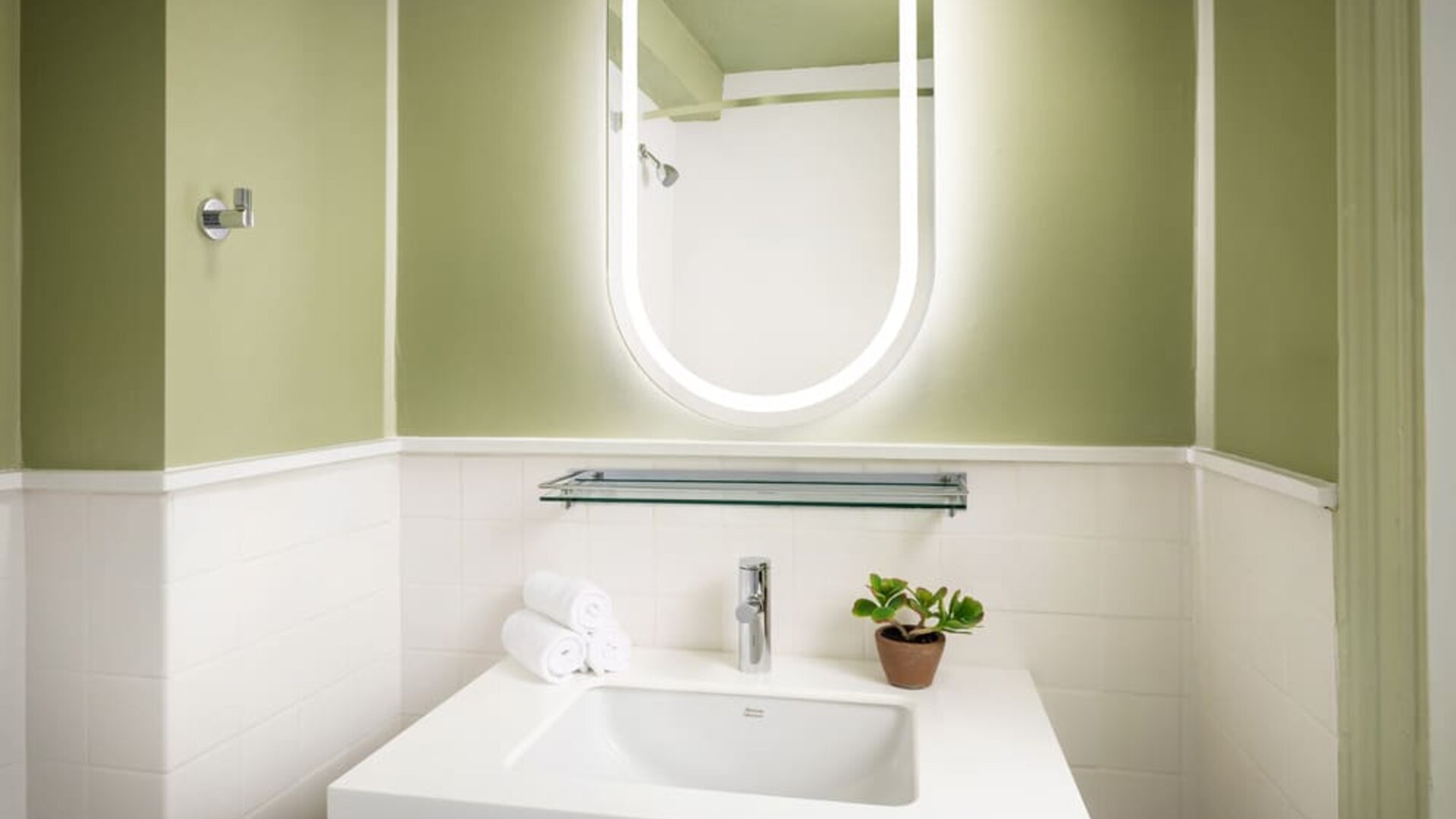Modern guest bathroom featuring a sleek vanity, illuminated mirror, and contemporary finishes designed for comfort and convenience at Row NYC.