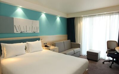 Day use room with king bed, work desk and sofa at the Hampton by Hilton London Docklands.