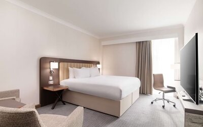 Day use room with work desk and chair, TV and sofa at the Hilton London Gatwick Airport.