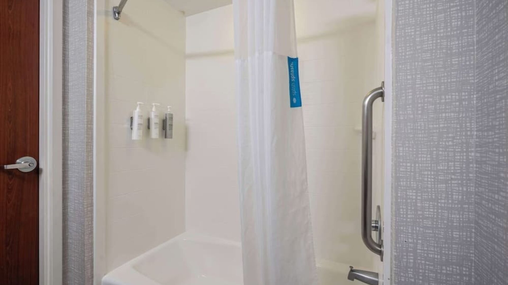 Accessible walk-in shower featuring grab bars, handheld showerhead, and convenient entry designed for a comfortable stay at Hampton Inn Ridgefield Park.