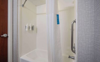 Accessible walk-in shower featuring grab bars, handheld showerhead, and convenient entry designed for a comfortable stay at Hampton Inn Ridgefield Park.