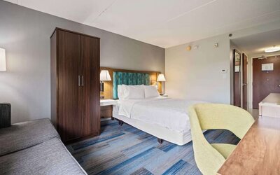 Spacious guest room featuring a plush king bed, ergonomic workspace, comfortable seating, and modern amenities for a relaxing stay at Hampton Inn Ridgefield Park.