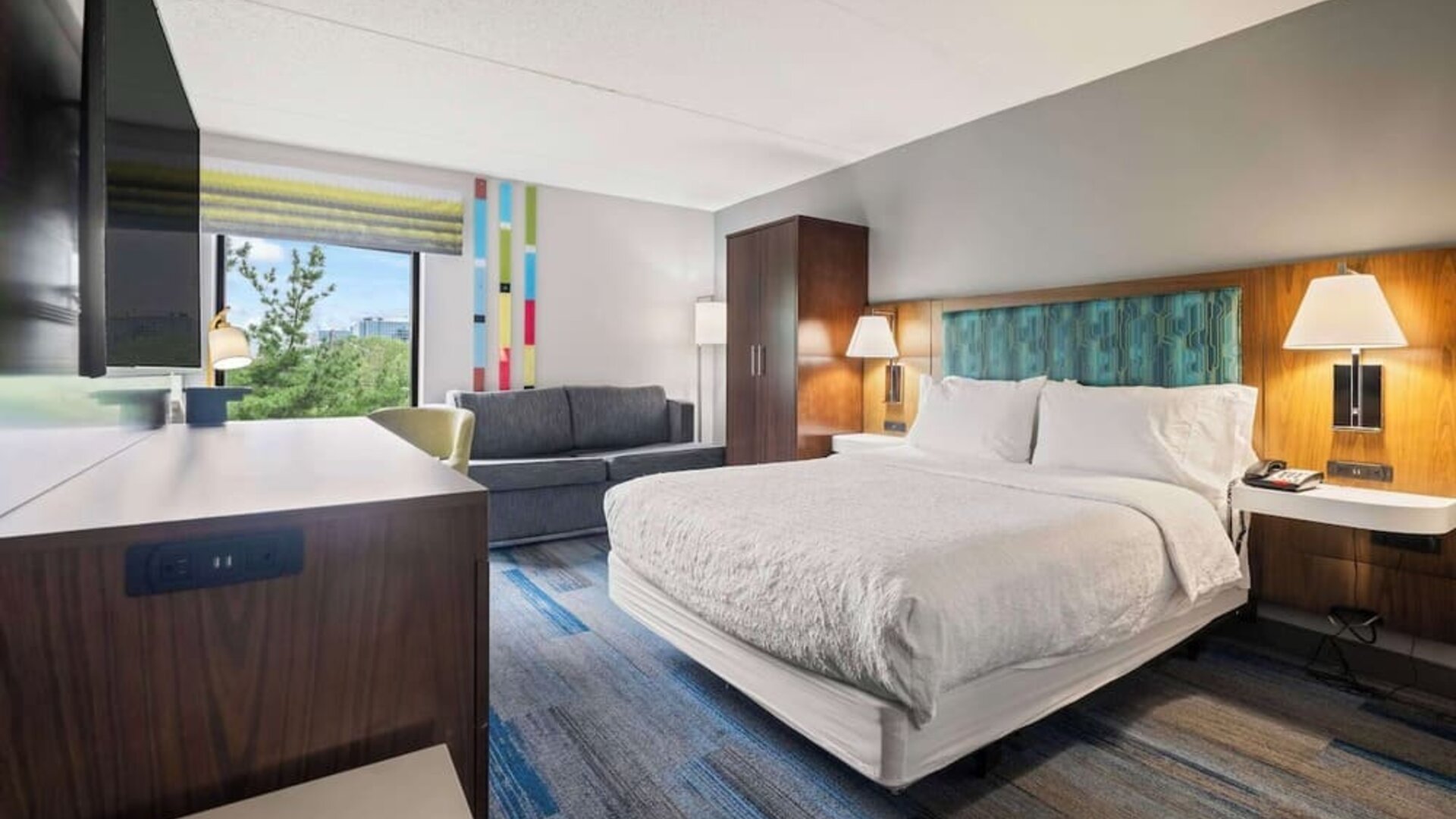 Spacious king guest room featuring contemporary furnishings, a comfortable sofa, ergonomic workspace, and premium bedding for a restful stay.