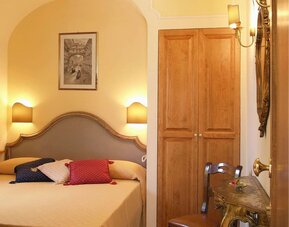 Bright and elegant guest room featuring a comfortable double bed, classic furnishings, and a writing desk.