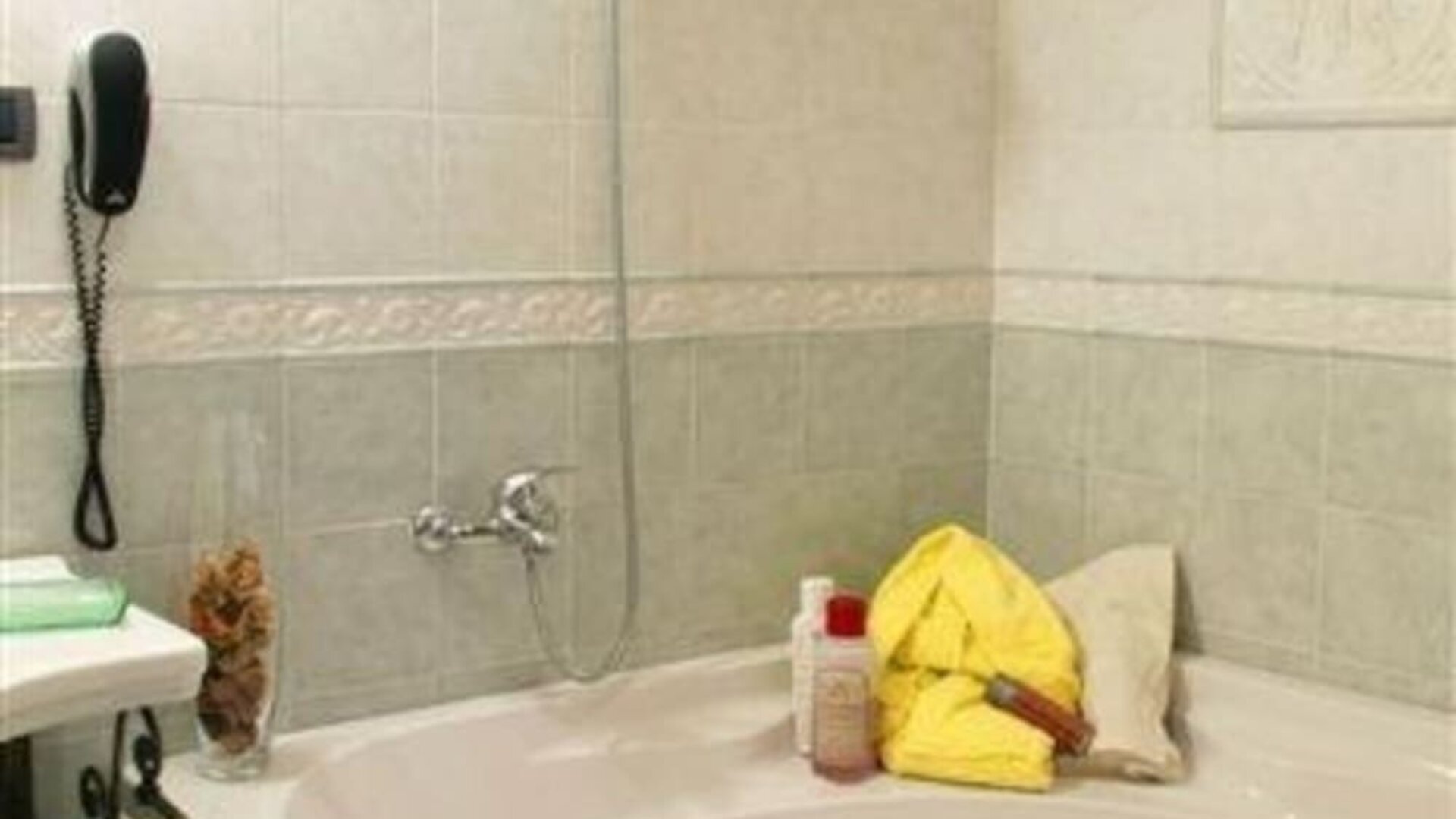 Spacious bathroom with a whirlpool bathtub, overhead shower, and elegant tiled finishes for a relaxing stay.