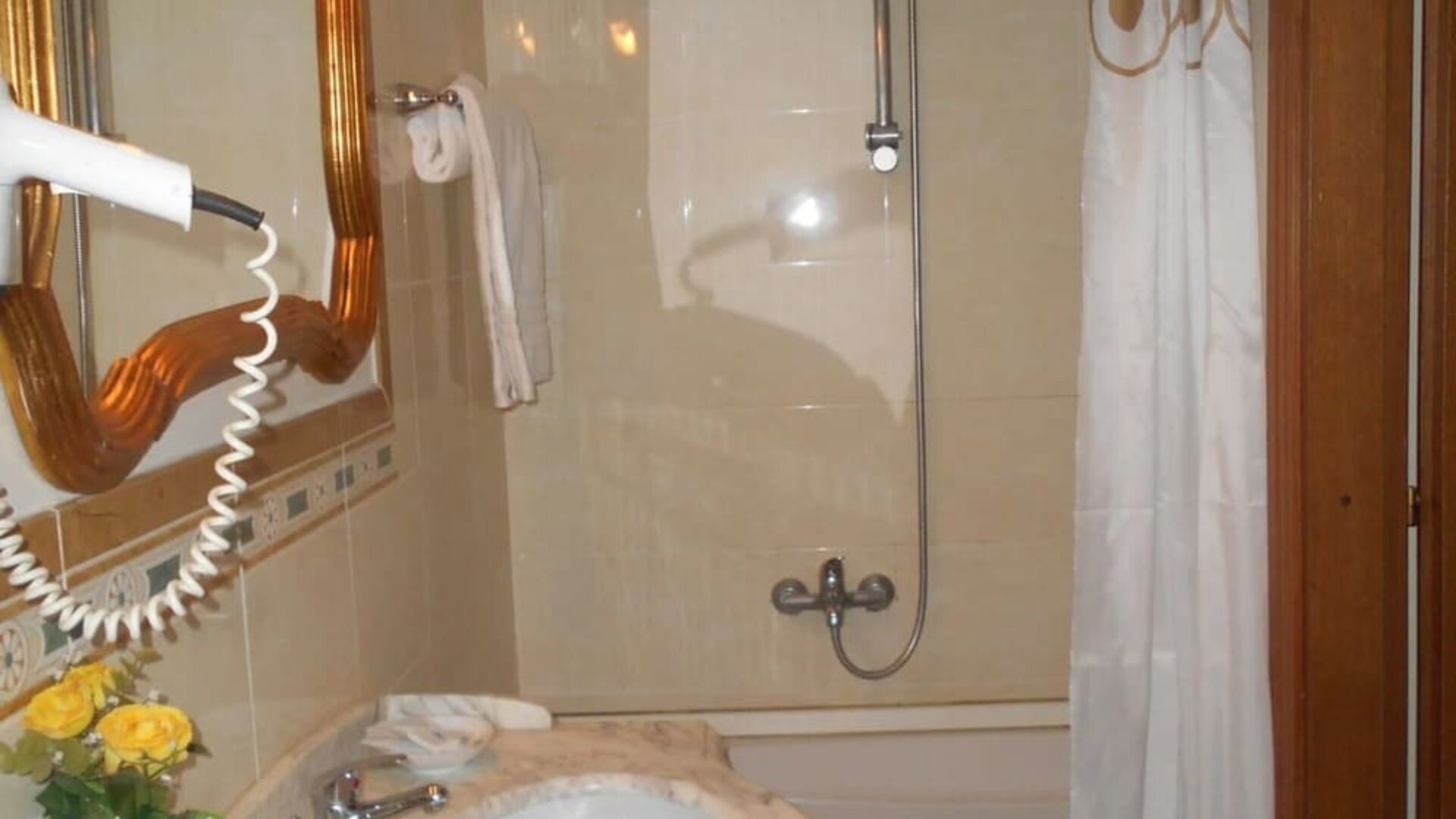 Bright bathroom with a marble vanity, bathtub with shower, hairdryer, and complimentary toiletries.
