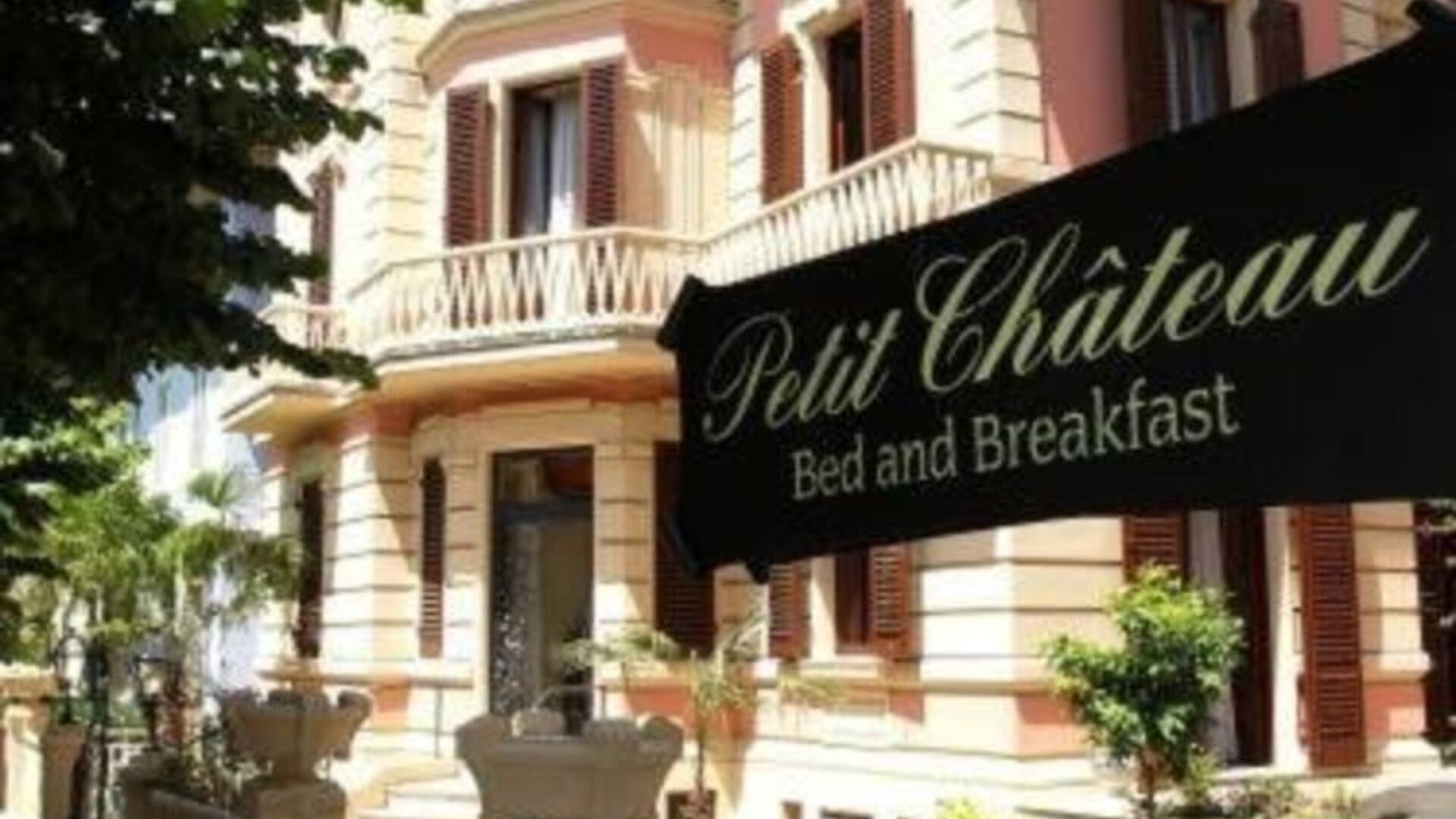 Exterior view of Petit Chateau showcasing its elegant villa architecture, landscaped gardens, and welcoming entrance.