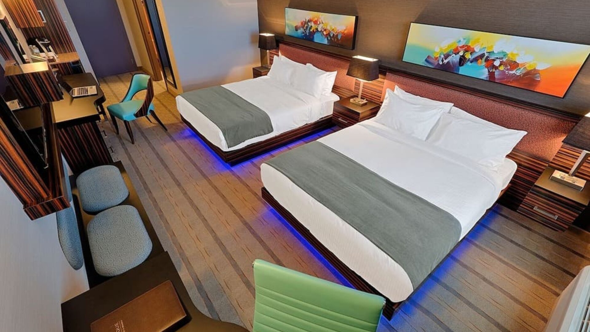 Guest room with two queen beds, workspace, seating area, and contemporary artwork above each headboard. Hotel Clique Calgary Airport.