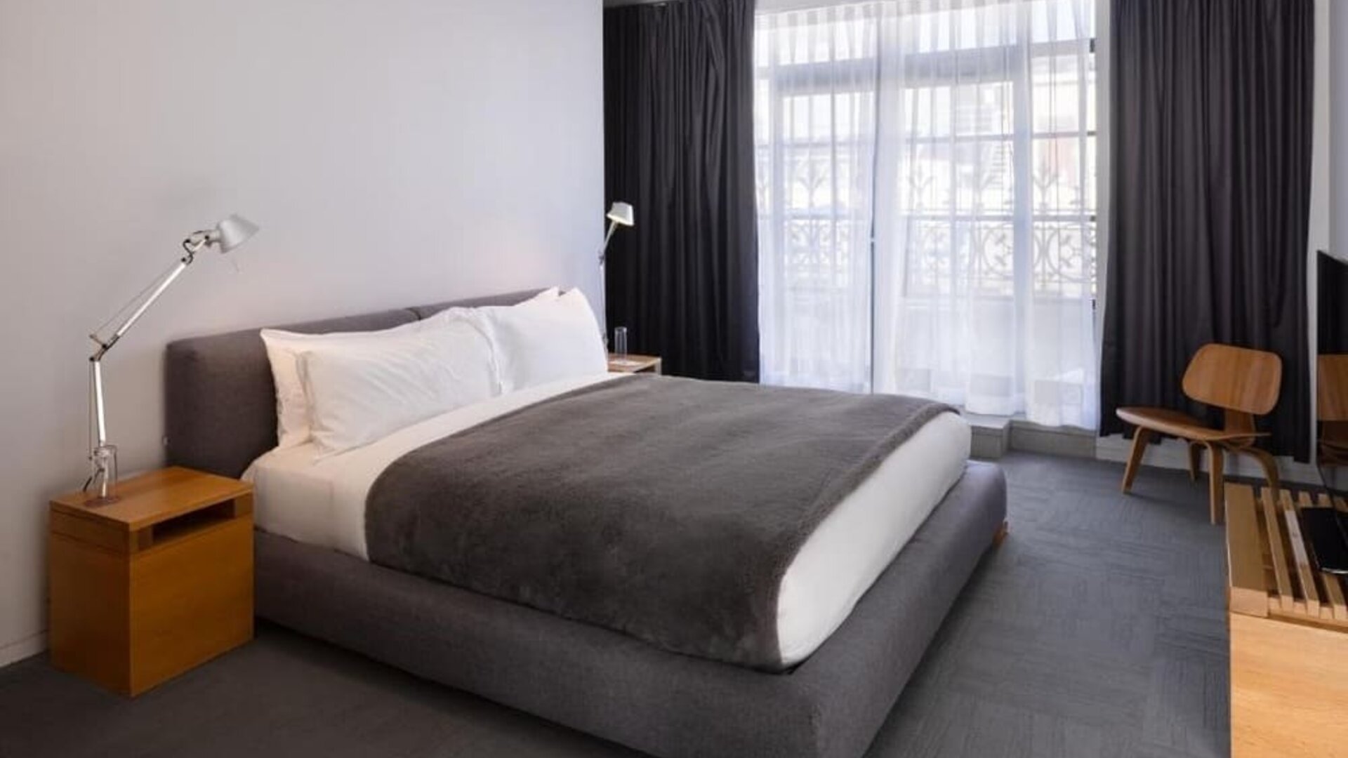 King guest room with floor-to-ceiling windows, modern lighting, lounge chair, and minimalist furnishings. Hotel Gault.