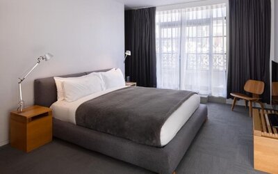 King guest room with floor-to-ceiling windows, modern lighting, lounge chair, and minimalist furnishings. Hotel Gault.