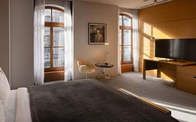 Spacious guest room with king bed, tall arched windows, seating area, and large flat-screen television. Hotel Gault.