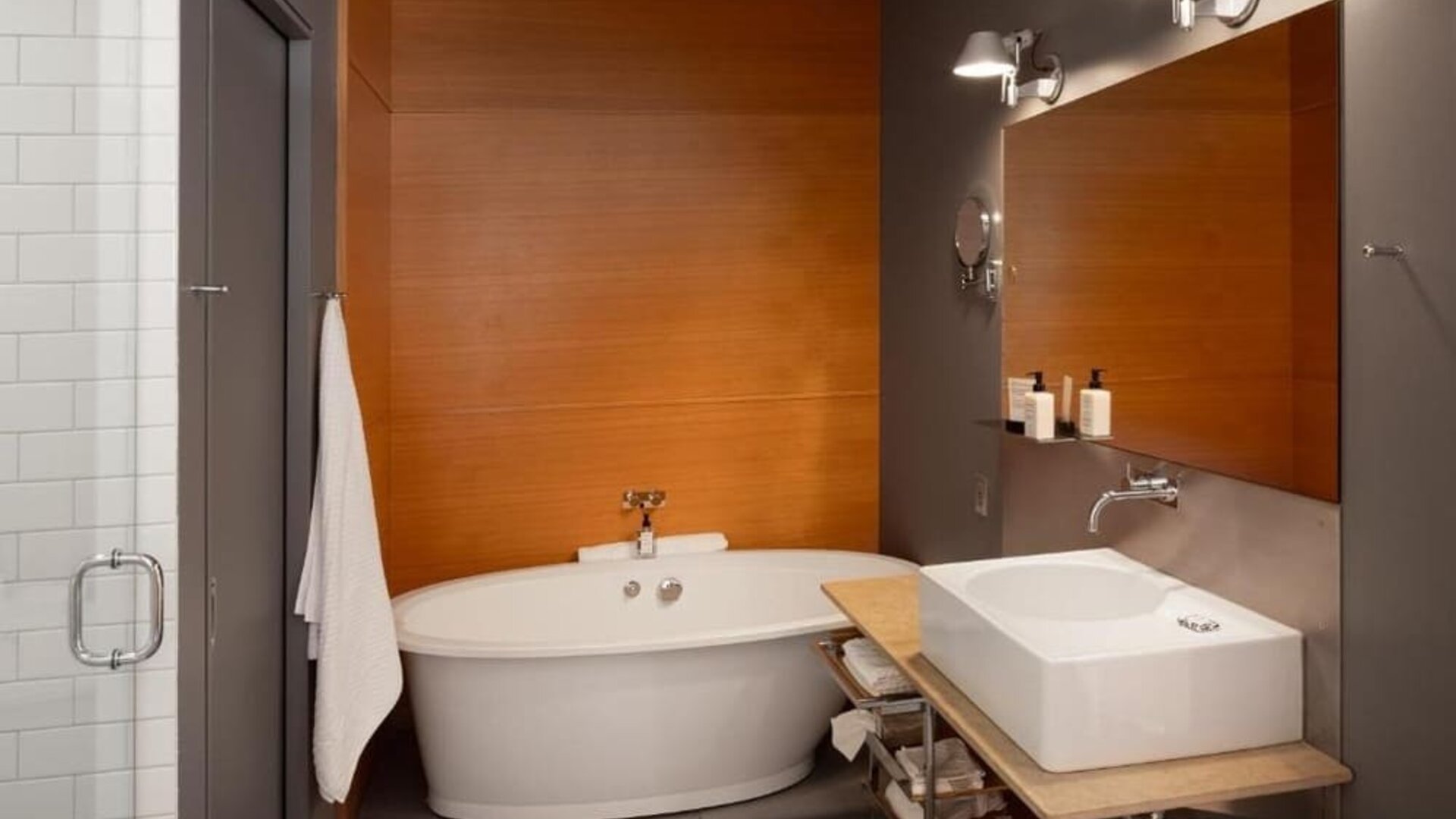 Contemporary bathroom with freestanding bathtub, floating sink, large mirror, and glass-enclosed shower. Hotel Gault.