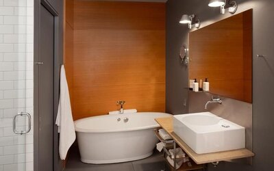 Contemporary bathroom with freestanding bathtub, floating sink, large mirror, and glass-enclosed shower. Hotel Gault.