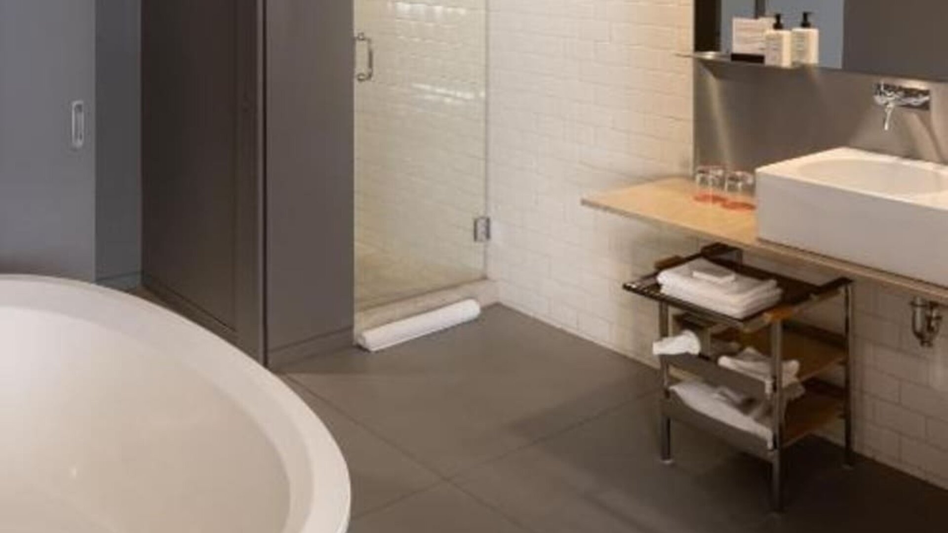 Modern bathroom with freestanding soaking tub, glass walk-in shower, floating vanity, and white subway tile walls. Hotel Gault.