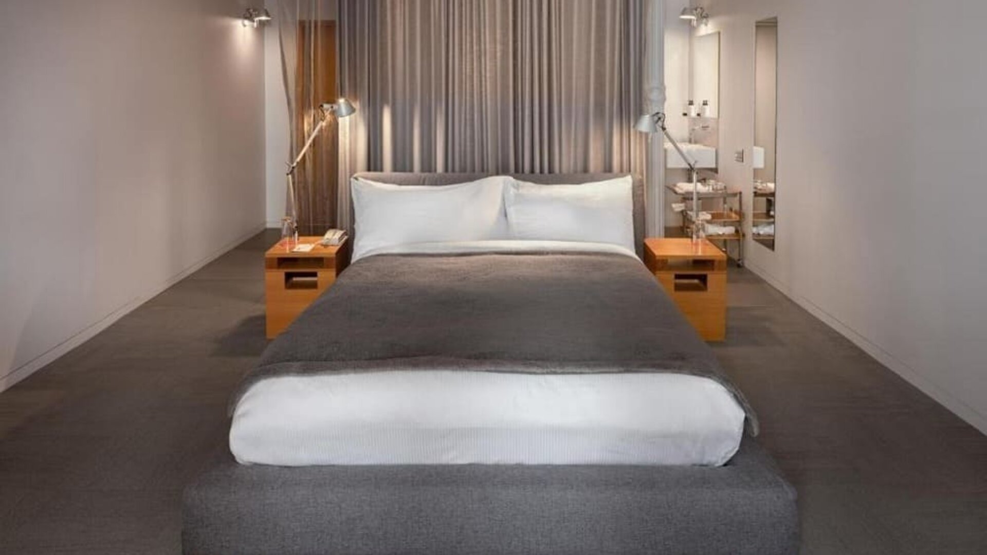 Minimalist guest room with platform king bed, bedside tables, and open bathroom entrance with modern fixtures. Hotel Gault.