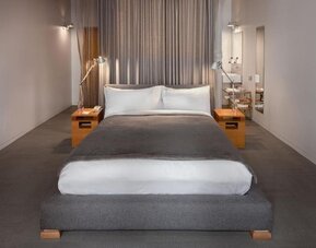 Minimalist guest room with platform king bed, bedside tables, and open bathroom entrance with modern fixtures. Hotel Gault.