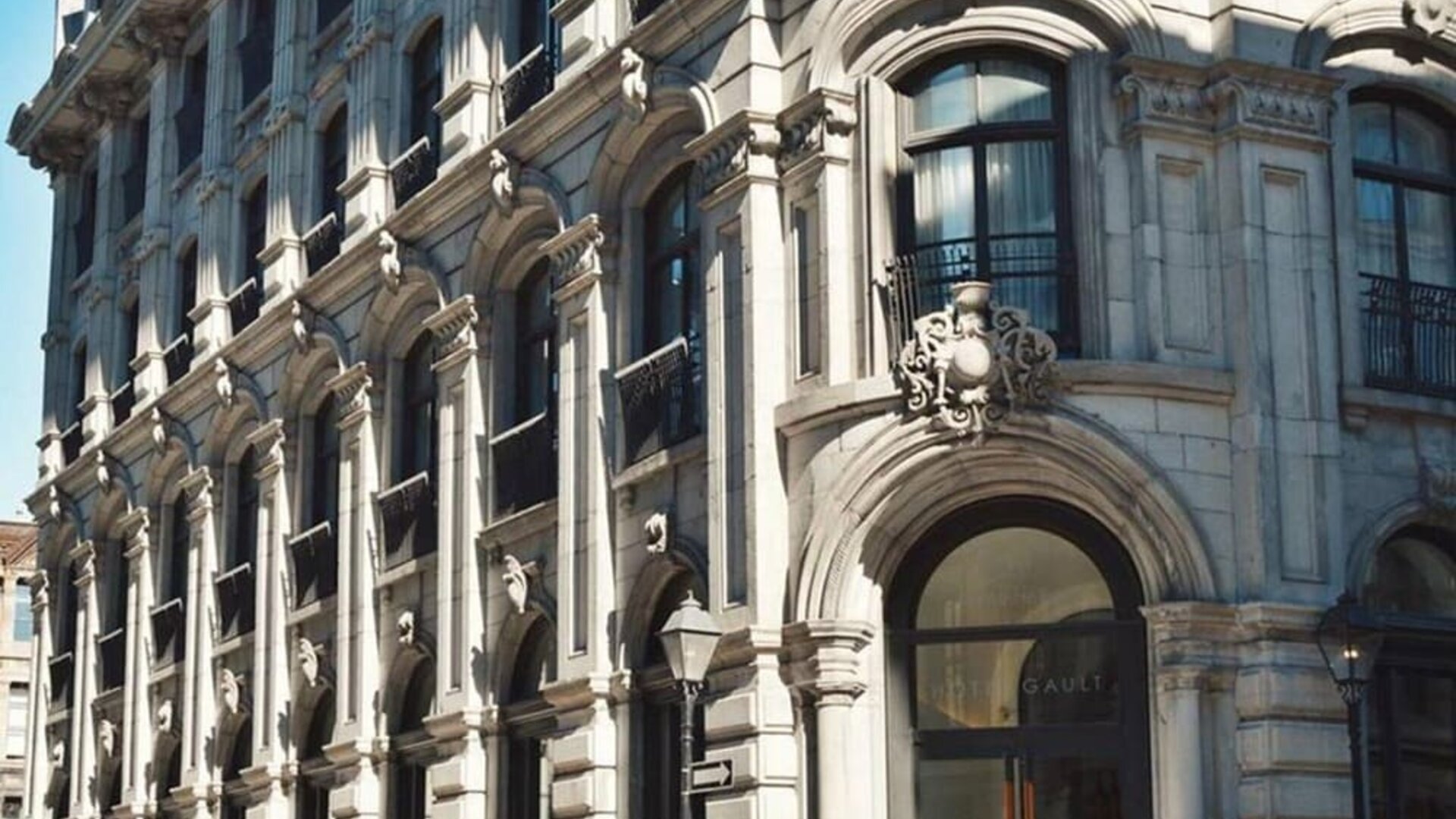 Historic stone façade with ornate architectural details, arched entrance, and large windows in daylight. Hotel Gault.