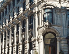 Historic stone façade with ornate architectural details, arched entrance, and large windows in daylight. Hotel Gault.