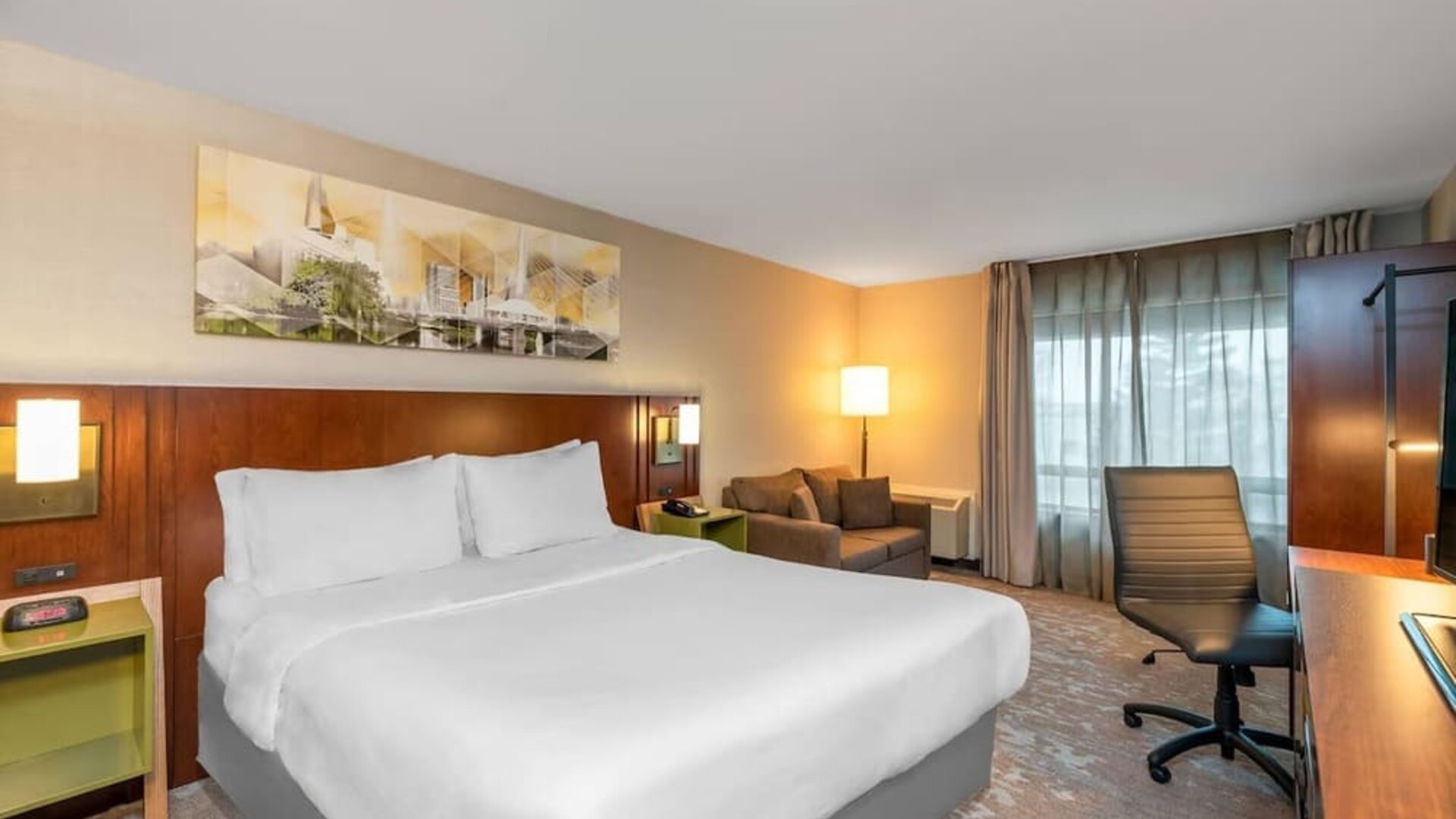 King guest room with work desk, sofa, large window, and contemporary décor at Comfort Inn Boucherville.