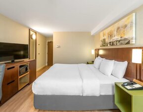 King guest room with work desk, flat-screen TV, microwave, and contemporary furnishings at Comfort Inn Boucherville.