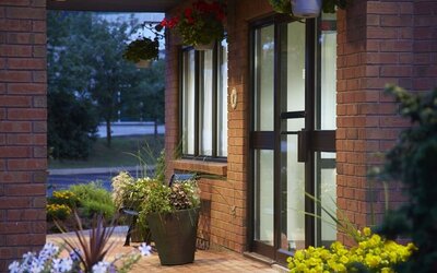 Hotel entrance with brick exterior, landscaped flower planters, and covered walkway at dusk at Comfort Inn Boucherville.