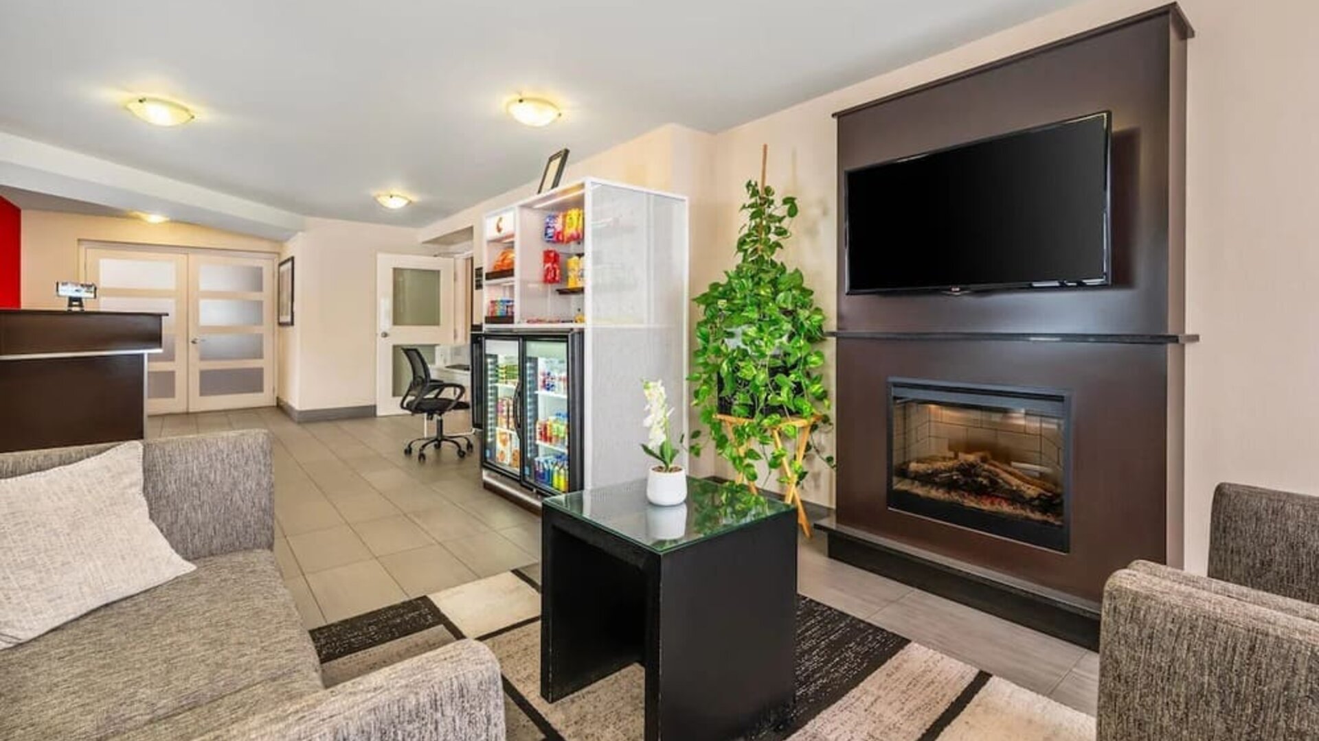 Hotel lobby with fireplace, flat-screen TV, snack market, and comfortable lounge seating at Comfort Inn Boucherville.