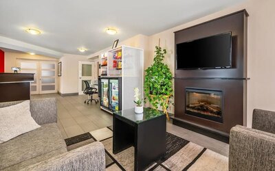 Hotel lobby with fireplace, flat-screen TV, snack market, and comfortable lounge seating at Comfort Inn Boucherville.