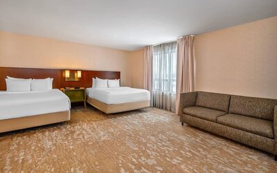 Spacious guest room with two queen beds, sofa, large window, and open floor layout at Comfort Inn Boucherville.