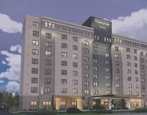 Contemporary hotel exterior with covered entrance and illuminated Hampton Inn signage at Hampton Inn By Hilton Montreal East Anjou.