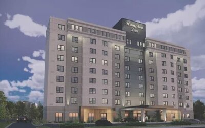 Contemporary hotel exterior with covered entrance and illuminated Hampton Inn signage at Hampton Inn By Hilton Montreal East Anjou.