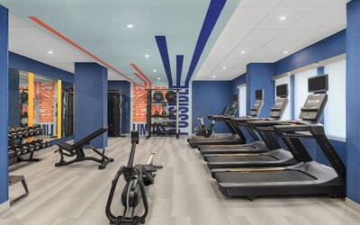 Spacious fitness room with treadmills, rowing machine, weight bench, and strength training equipment at Hampton Inn By Hilton Montreal East Anjou.