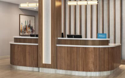 Reception desk with wood paneling, Hilton Honors signage, and contemporary lighting at Hampton Inn By Hilton Montreal East Anjou.