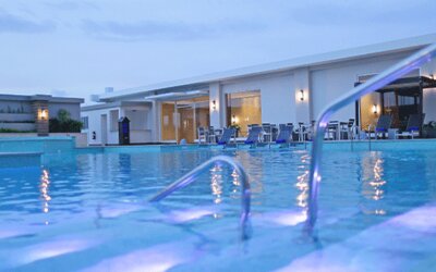 Outdoor swimming pool area at Crowne Plaza Panama Airport with spacious lounging areas and evening lighting, offering a relaxing environment for guests.