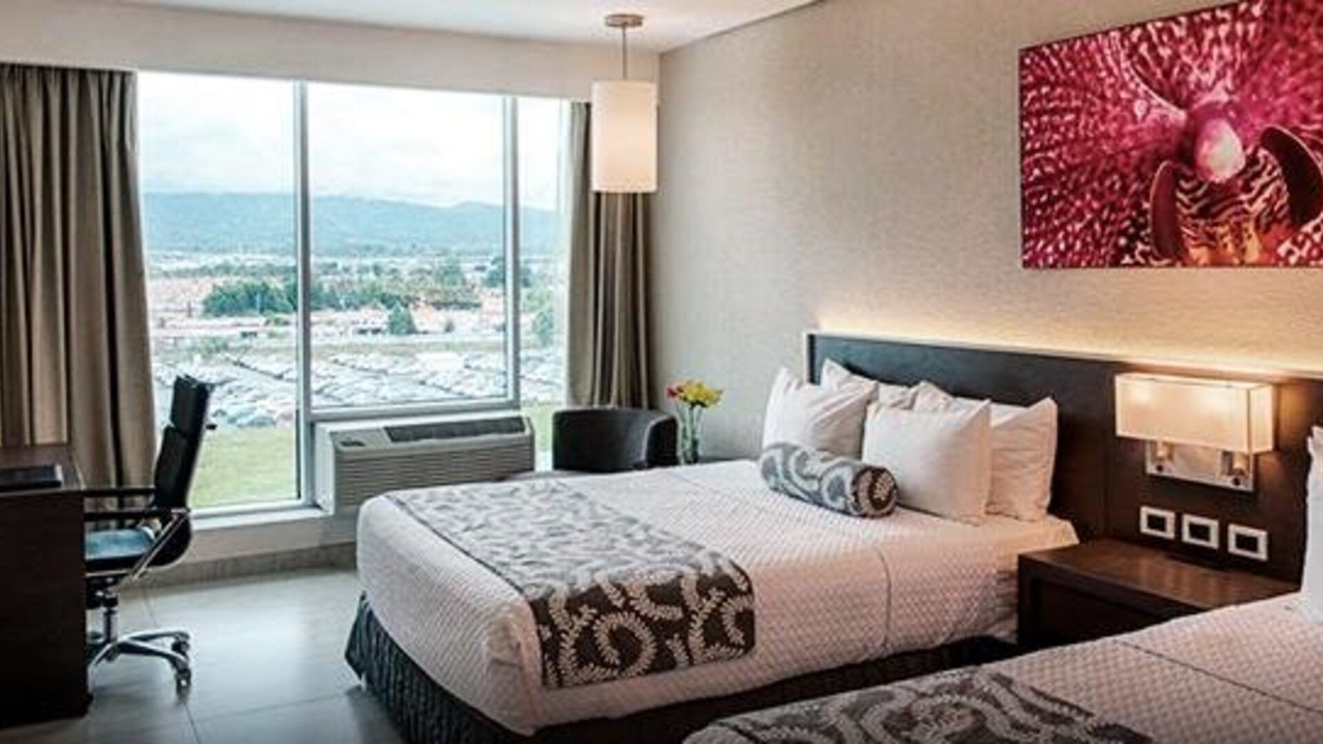 Modern guest room at Crowne Plaza Panama Airport featuring two comfortable beds, a workspace, large windows with city views, and contemporary décor designed for both business and leisure travelers.