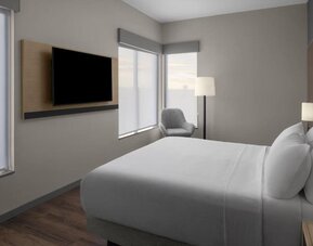 King guest room with large windows, wall-mounted television, lounge chair, and contemporary furnishings at Hyatt Place Bozeman Yellowstone Airport.