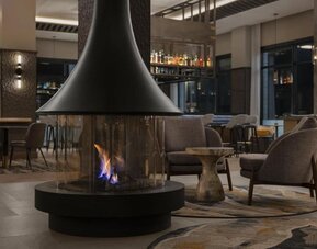 Modern lobby lounge featuring a suspended fireplace, comfortable seating, and inviting social spaces at Hyatt Place Bozeman Yellowstone Airport.