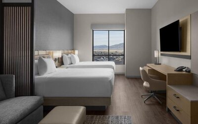 Guest room with two queen beds, work desk, sofa, and scenic mountain views at Hyatt Place Bozeman Yellowstone Airport.