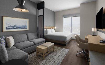Spacious king guest room with sofa, work desk, and modern furnishings at Hyatt Place Bozeman Yellowstone Airport.