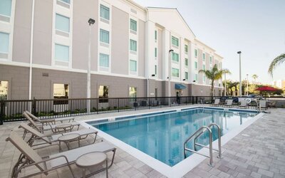 Outdoor swimming pool with lounge chairs and spacious sun deck at Hampton Inn & Suites Orlando at SeaWorld.