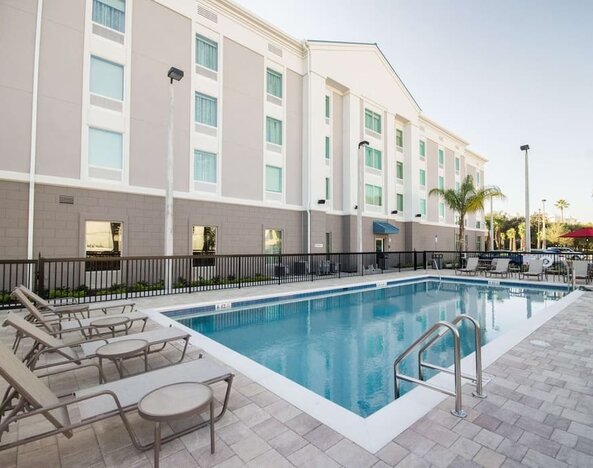 Outdoor swimming pool with lounge chairs and spacious sun deck at Hampton Inn & Suites Orlando at SeaWorld.