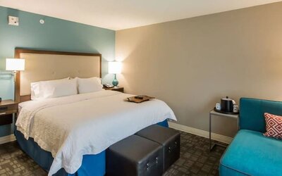 King guest room with comfortable bed, lounge chair, and contemporary décor at Hampton Inn & Suites Orlando at SeaWorld.