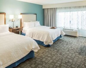 Spacious guest room with two queen beds, work desk, and large window at Hampton Inn & Suites Orlando at SeaWorld.