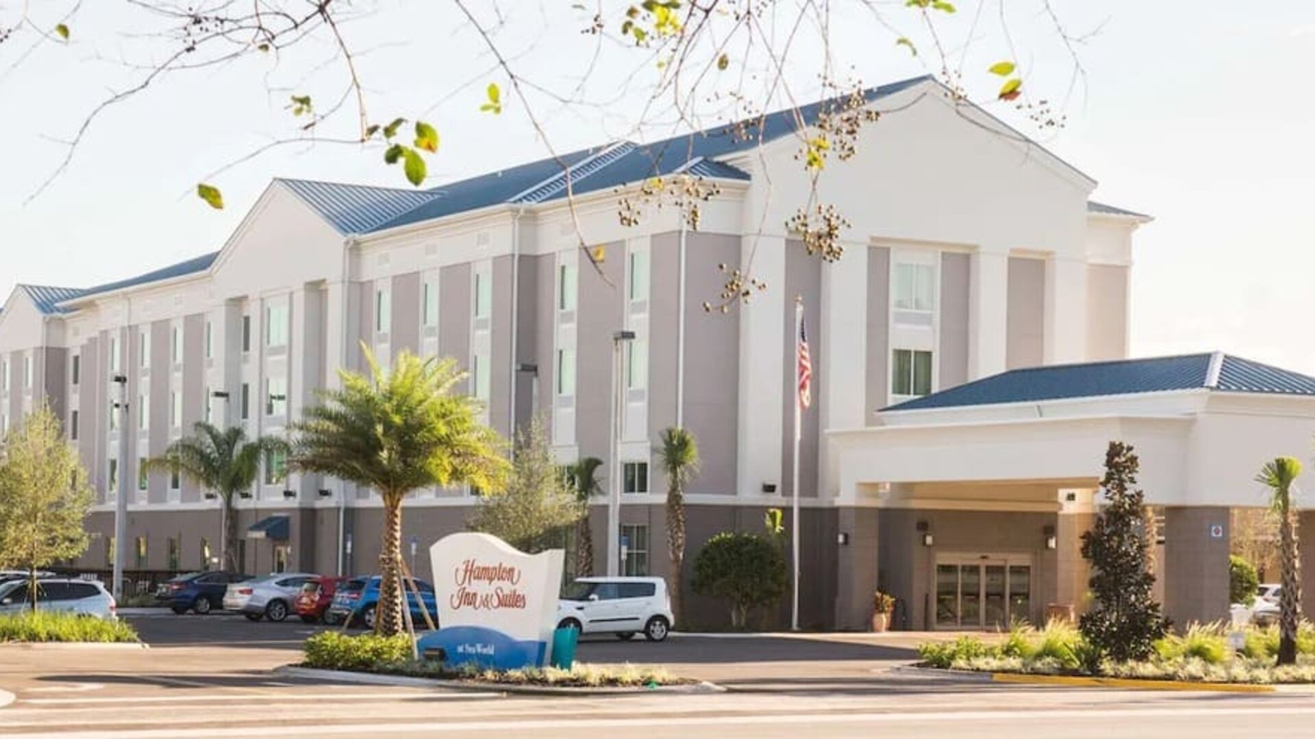 Hotel exterior with covered entrance, landscaped grounds, and guest parking at Hampton Inn & Suites Orlando at SeaWorld.