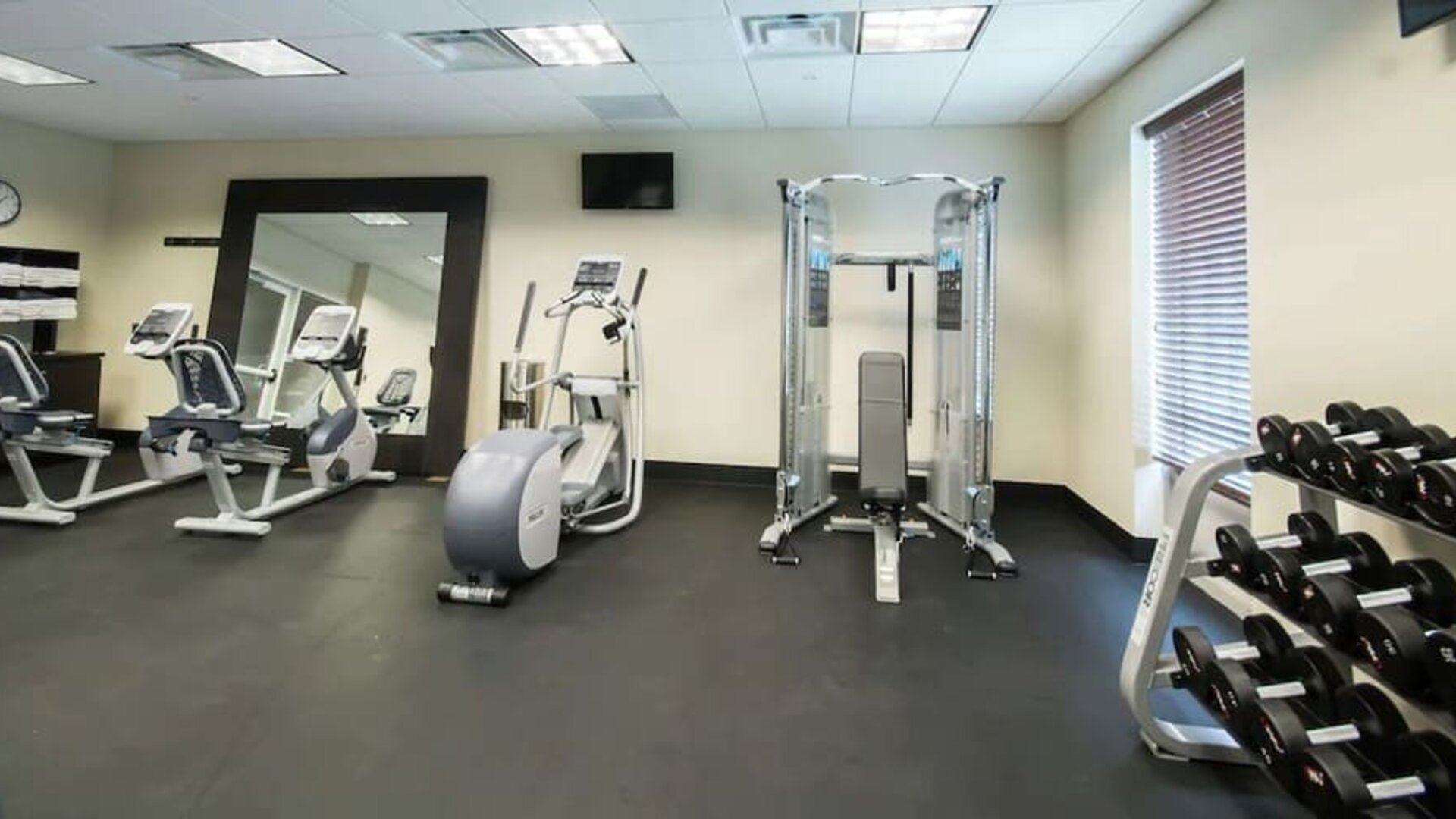 Fitness facility with strength training equipment, cardio machines, and dumbbell rack at Hampton Inn & Suites Orlando at SeaWorld.