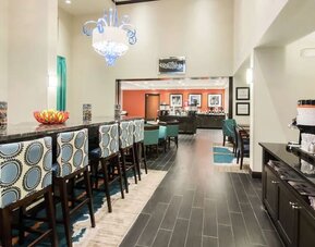 Hotel dining area with coffee station, communal seating, and breakfast service at Hampton Inn & Suites Orlando at SeaWorld.