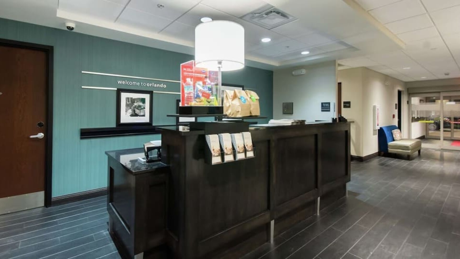 Front desk with guest services counter and modern lobby entrance at Hampton Inn & Suites Orlando at SeaWorld.